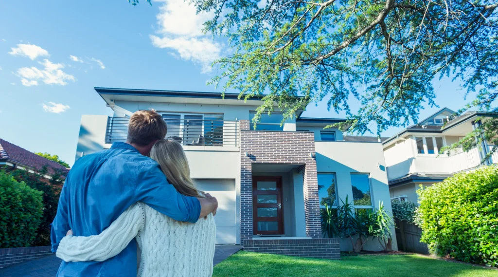Happy couple standing in front of their new house after investing in U.S. real estate