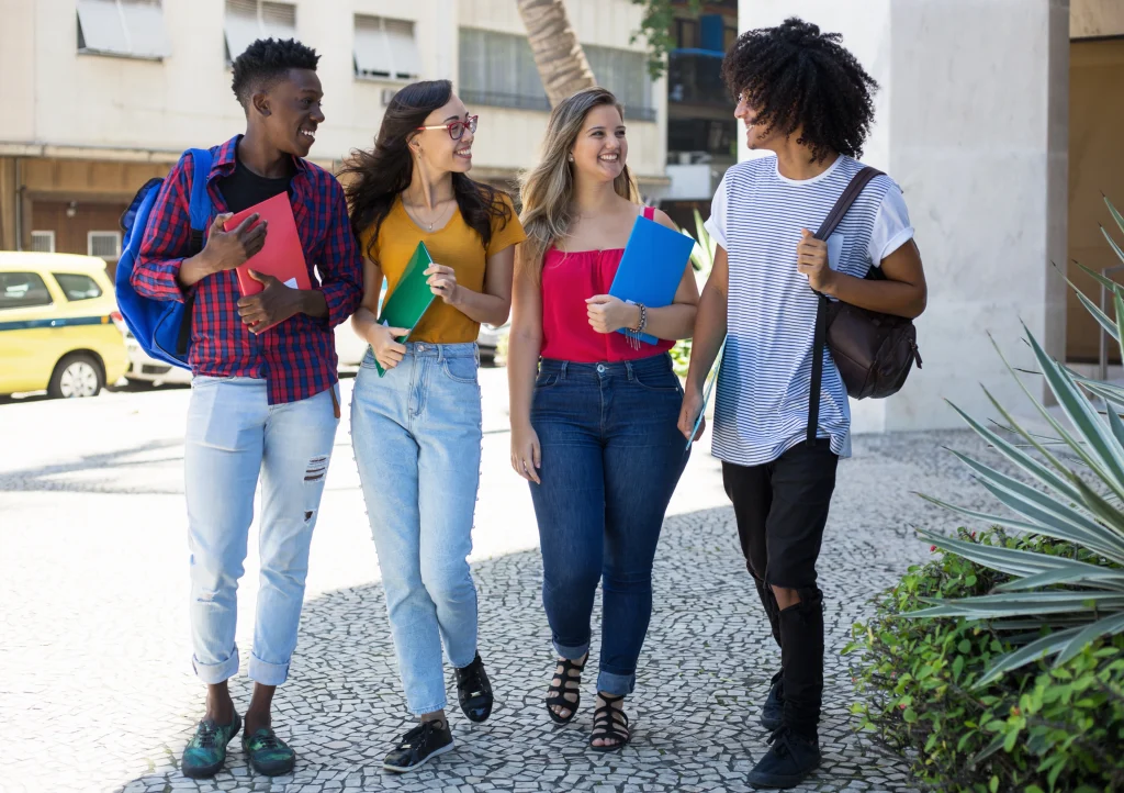 Group of diverse college students walking and chatting happily, representing student housing investment opportunities in Ohio.