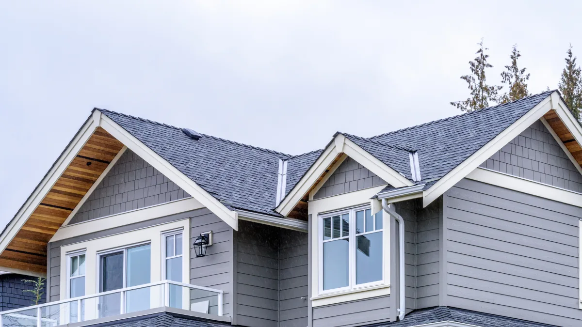 A close-up view of the upper section of a modern house featuring a gray exterior and a sloped roof during Adobestock 426724173.