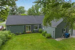 Backyard view of a single-family home with green siding and a well-maintained lawn